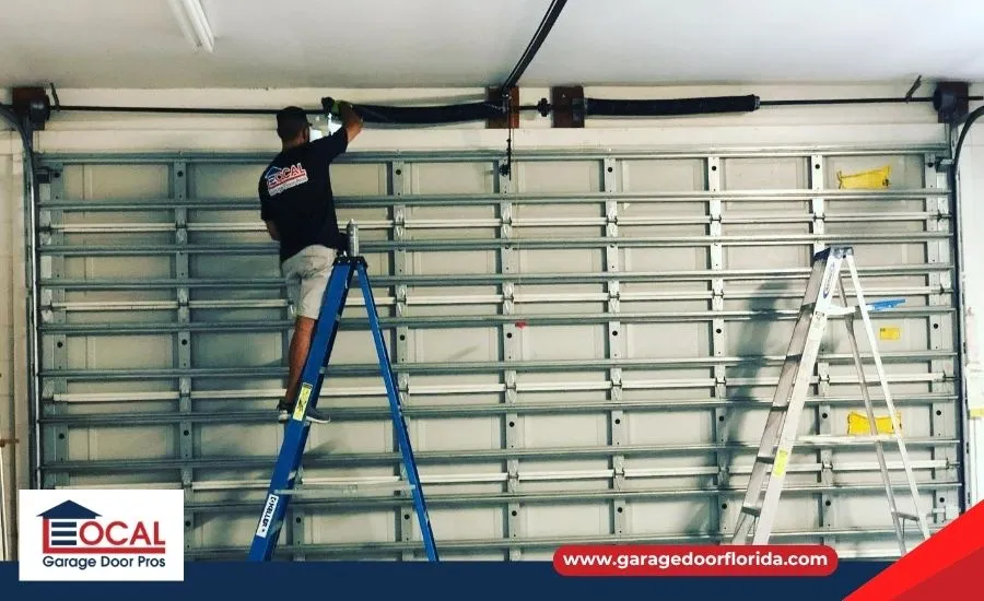 A professional garage door technician in uniform safely installing or adjusting the high-tension torsion springs on a new residential garage door.