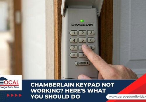 A person's finger pressing a button on a Chamberlain wireless garage door keypad mounted outside.