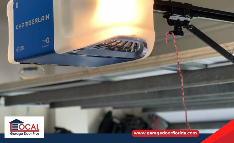A blue and white Chamberlain garage door opener unit with its overhead light turned on.