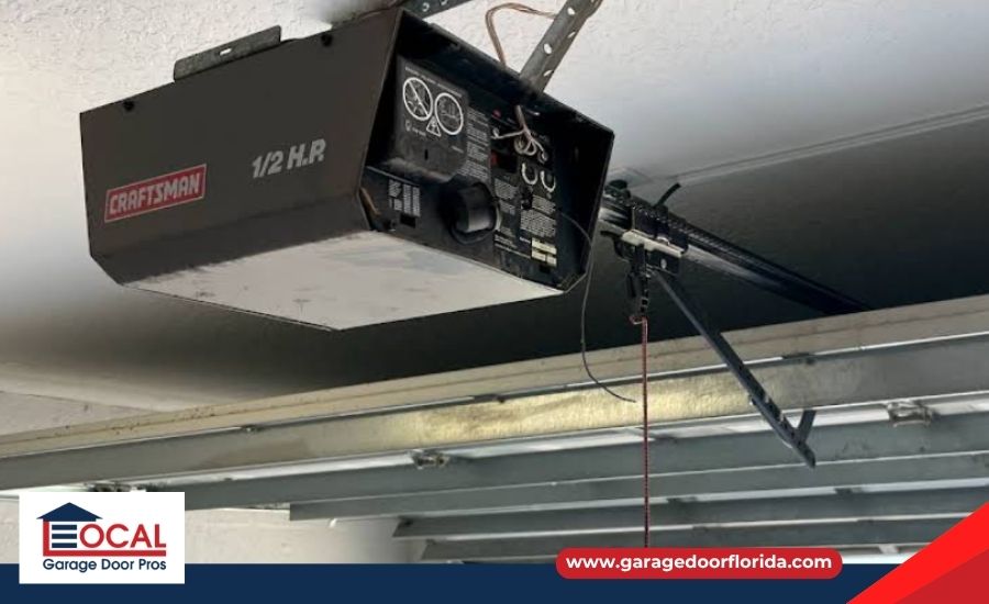 An older half-horsepower Craftsman garage door opener motor unit mounted to a ceiling.