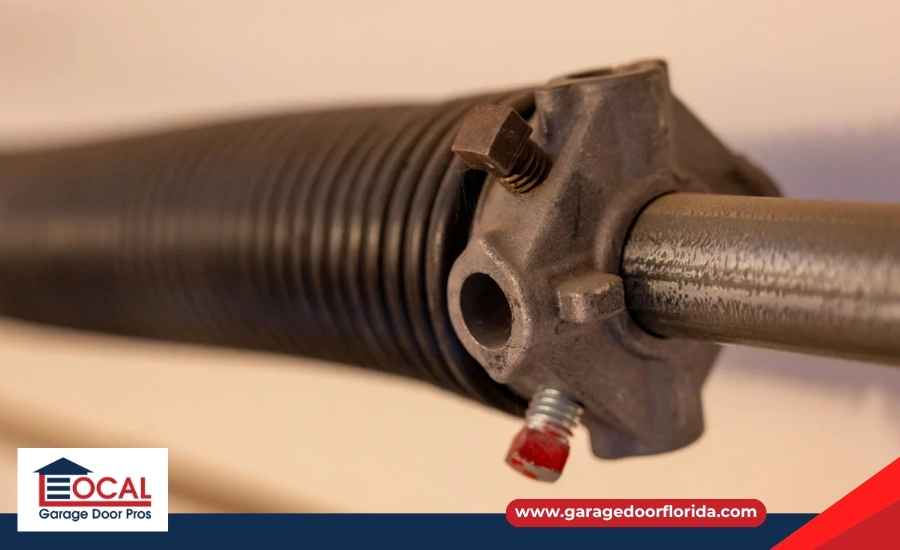 A close-up view of a heavy-duty steel torsion spring mounted above a garage door.