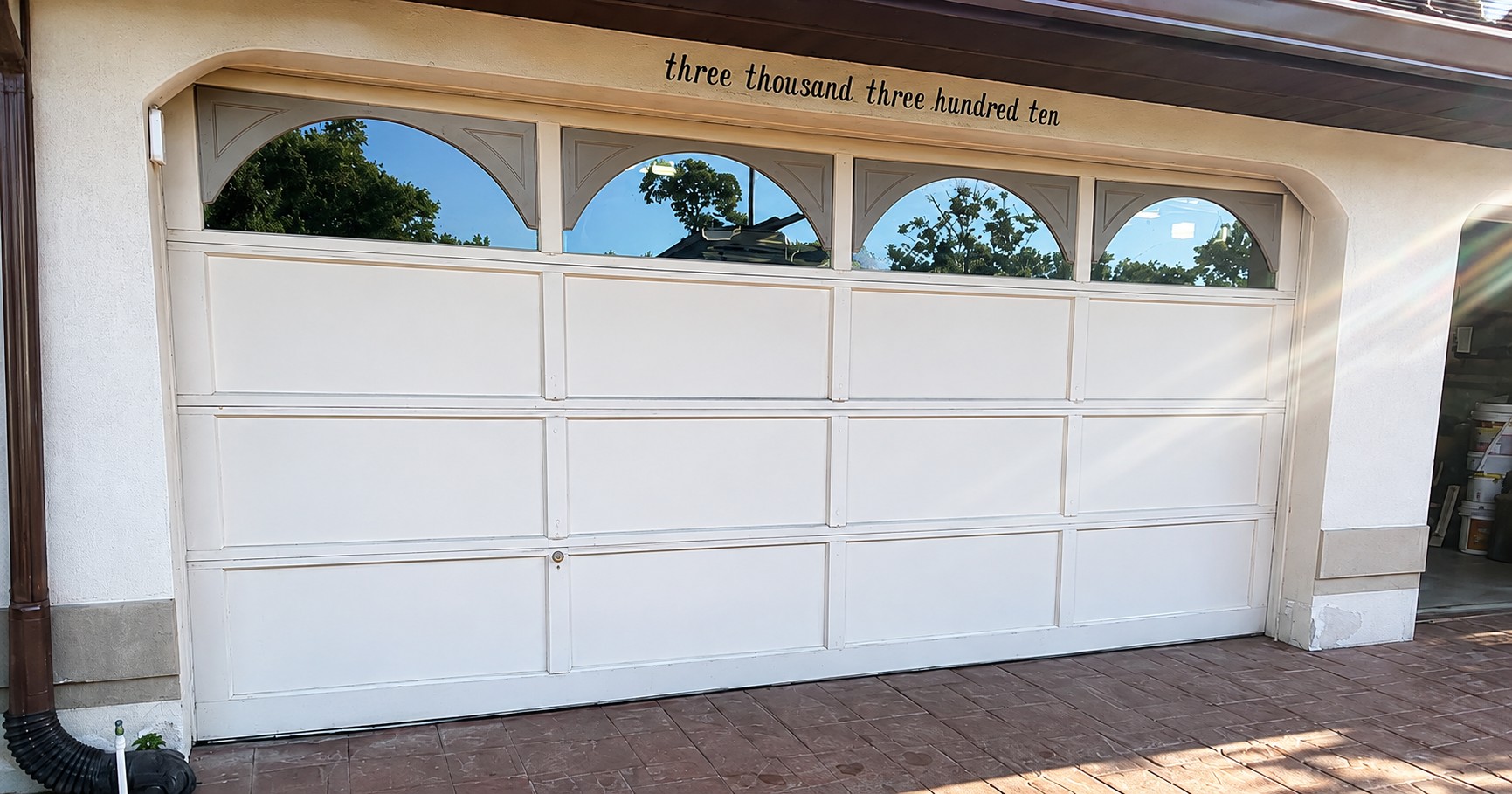 Before: older white garage door with arched window panels