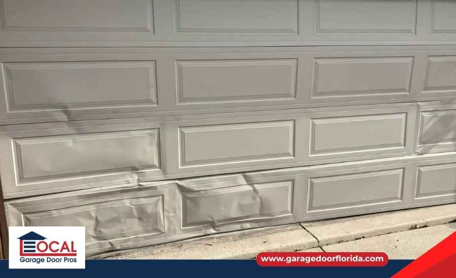 Damaged garage door panel with dented metal and surface wear