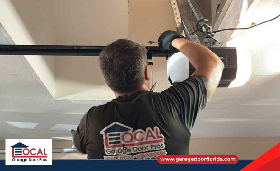 Professional technician with tools inspecting a garage door track and opener